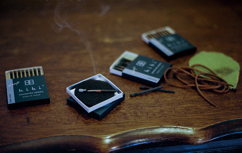Four cases of hibi deep series incense matches placing on the table, opened, one of them is burning on the mat