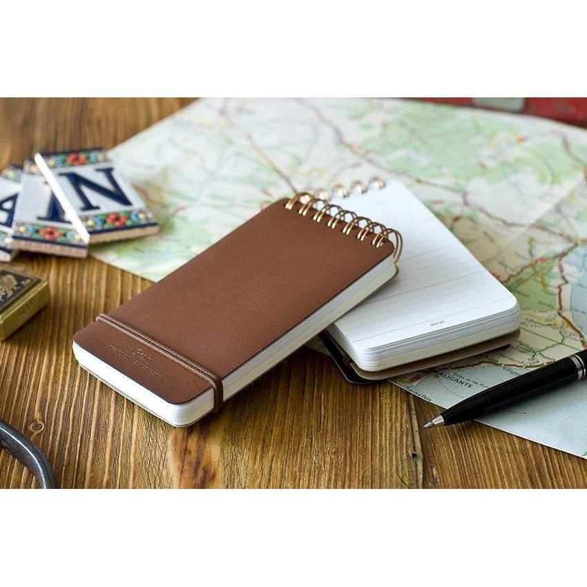 two midori grain leather notepad stacked in a background of maps and notebooks