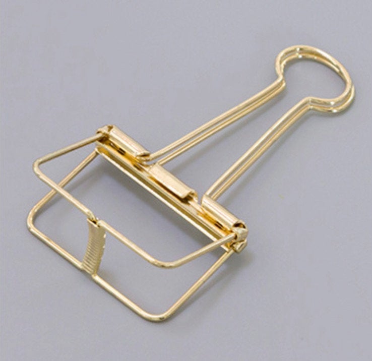 A golden skeleton paper clip in detail, in gray background