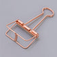 A rose gold skeleton paper clip in detail, in gray background