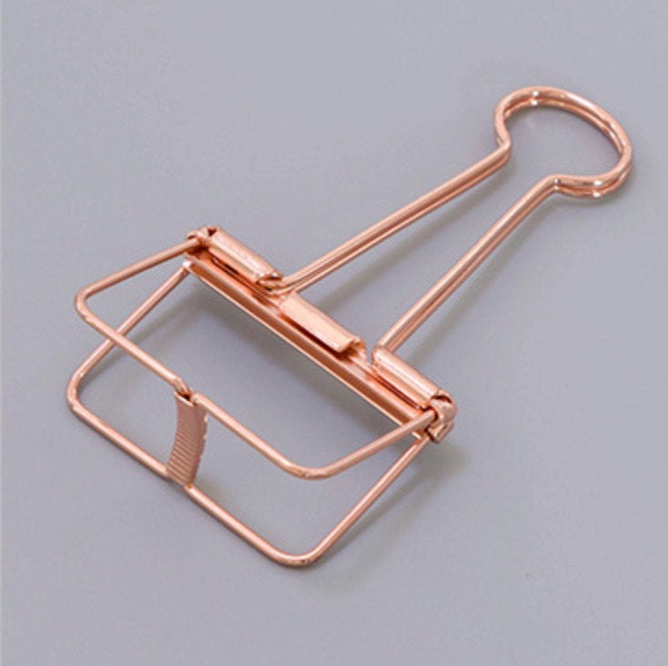 A rose gold skeleton paper clip in detail, in gray background
