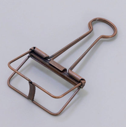 A matte brown skeleton paper clip in detail, in gray background