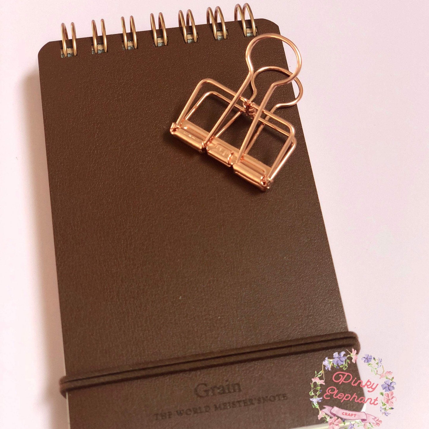 One rose gold skeleton paper clips placing on a flip leather cover memopad