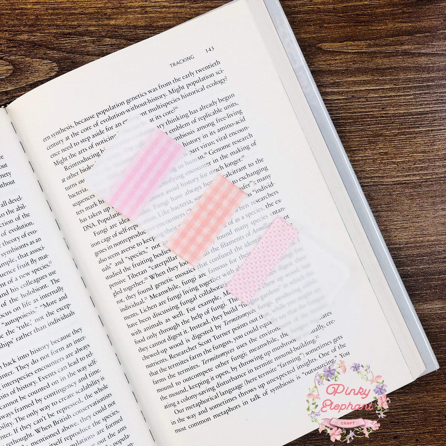 A sample washi tape card with pink grid and dotted washi tape placing on a opened novel.